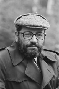 Phot of Italian writer Umberto Eco. A middelaged man with flat pet, glasses a beard and mustache and a coat.